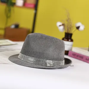 Dark grey fedora hat with silver rhinestone band and metal buckle in a warm studio setting