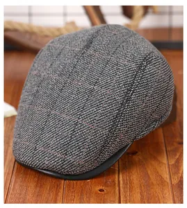 Detailopname van grijze tweed pet met ruitpatroon en een zwarte leren rand