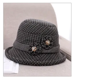 Close-up of grey houndstooth wool hat with floral applique and rhinestones on a sofa