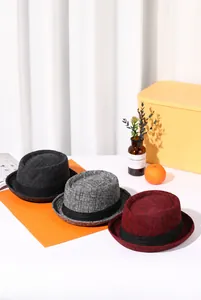 Three pork pie hats in grey plaid and dark red shown in an elegant lifestyle setting