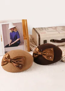 Close-up of wool beret featuring elegant satin bow with delicate pearl embellishments