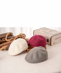 Detail of wool octagonal beret hats in beige, burgundy, and dark grey with a vintage texture