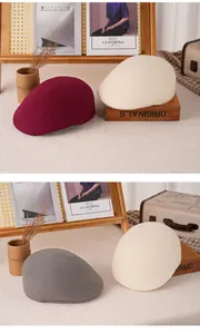 Trois bérets en laine feutrée bordeaux, beige et gris sur un support en bois vintage
