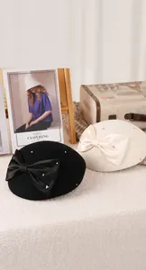 Detailed view of wool berets in black and beige with large satin bows and rhinestones