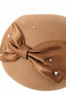 Detailed close-up of brown wool hat with large satin bow pearl and rhinestone embellishments