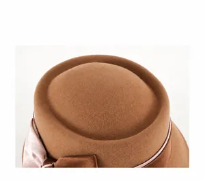 Close-up detail showing the fine texture of brown wool felt and satin ribbon decoration