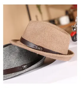 Detail view of wool fedora with leather band and metal M logo on khaki and gray fabric