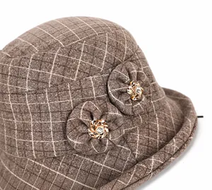 Detail of dark brown plaid wool hat featuring fabric flower decor and crystal metal center
