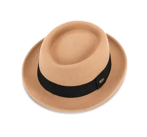 Détail d'un chapeau en laine camel avec ruban noir et boucle métallique dorée chic