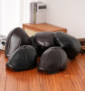 Detail von Vintage PU-Leder Schirmmützen in Schwarz und Braun auf rustikalem Holztisch