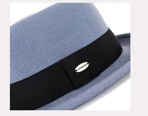 Détail d'un chapeau en feutre de laine bleu clair avec ruban noir et plaque dorée