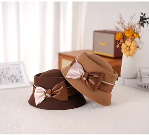 Detail of wool cloche hats in coffee and camel colors featuring satin bow decoration