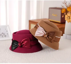 Detail of wool felt cloche hats in burgundy and camel with elegant bow decorations