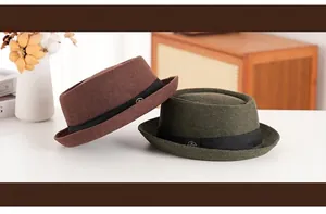 Detail of wool pork pie hats in dark brown and olive green with black ribbon and metal pin