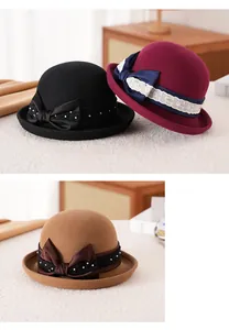 Dettaglio di cappelli cloche in lana con fiocco in raso e pizzo in nero, rosso e cammello