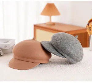 Detailopname van wollen baretten in camel en grijs op een wit imitatiebont tapijt