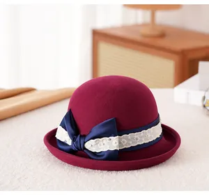 Dettaglio cappello in feltro di lana bordeaux con fiocco in raso blu e ricami in pizzo