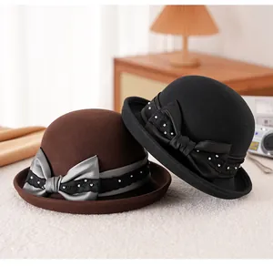 Dettaglio di cappelli cloche in lana con fiocchi di raso pieghettati e pizzo nero e marrone