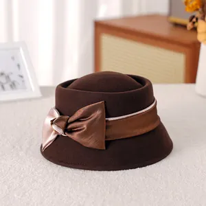 Elegant dark brown wool cloche hat for women with a silk bow on a cozy white rug