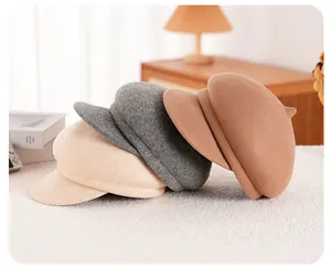 Drie wollen baretpetten in beige, grijs en camel in een warme huiselijke setting