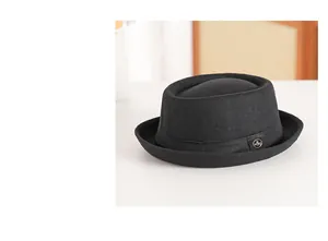 Detail of a black wool pork pie hat featuring a side metal badge and curled brim