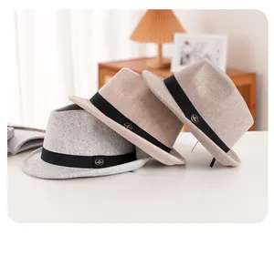 Detail of wool felt fedora hats in grey and beige with elegant grosgrain ribbon and metal logo