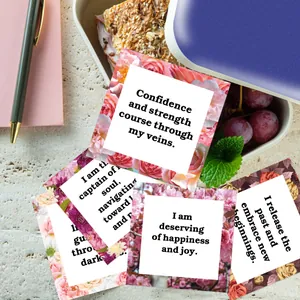 Detailed close-up of square floral affirmation cards with inspirational quotes in a lunchbox
