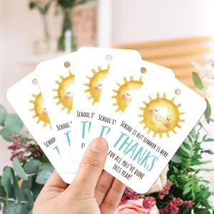 Close-up of summer teacher gift tags held by hand featuring yellow sun and school is out text