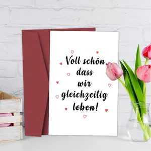 Primer plano de tarjeta de felicitación alemana con corazones y sobre color rojo burdeos