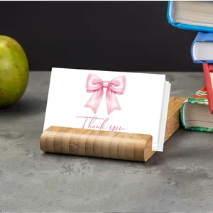 Bamboo card holder with Thank You notes and pink ribbon design on a modern office desk