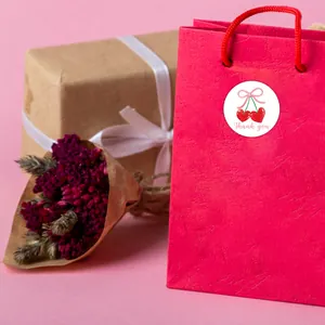 Close-up of a cherry heart thank you sticker on a pink gift bag with dried flowers