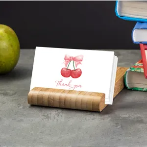 Close-up of a wooden base holding a white thank you card with a cherry pattern