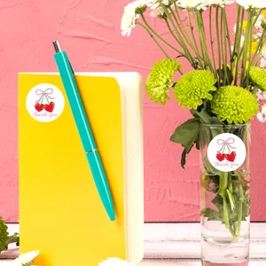 Detail of round cherry thank you stickers applied on notebook and glass vase decor