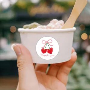 Close-up of a pink cherry thank you sticker applied on a white paper cup packaging