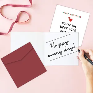 Detailed view of a white Christmas card for wife with red envelope on a pink background