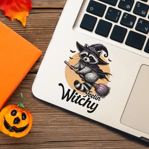 Halloween UV DTF transfer sticker of a witch raccoon on a laptop palm rest