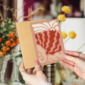Close-up of minimalist floral art thank you card held by hand with a kraft envelope