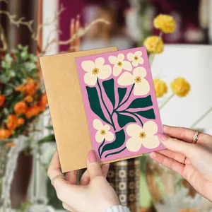 Close-up of floral art card and kraft envelope held by hand for scale and texture