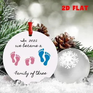 Makro-Detail eines runden weißen Acryl-Weihnachtsanhängers mit Baby-Fußabdrücken und 2025 Text
