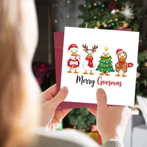 Hand holding a Merry Goosmas funny Christmas card with cute ducks and burgundy envelope
