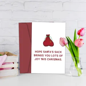 Grappige kerstkaart met kerstmanzak illustratie en rode envelop op een wit bureau