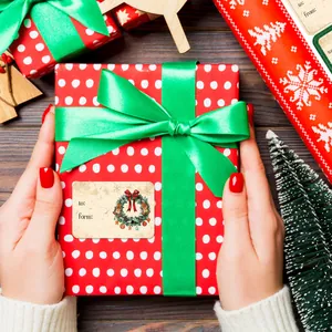 Nahaufnahme von Vintage-Weihnachtsanhängern mit Stechpalmenkranz und grünem Satinband auf Rot
