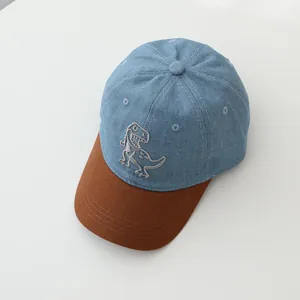 Close-up of children's dinosaur baseball cap with blue denim and brown brim details