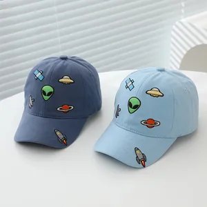 Detailed close-up of cartoon alien and spaceship embroidery on a blue kids baseball cap