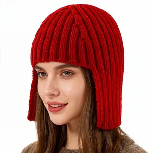 Detailed close-up of the red knitted winter hat texture and thick ear protection flaps