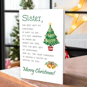 Close-up of a Christmas card for sisters on wooden table with festive background decor