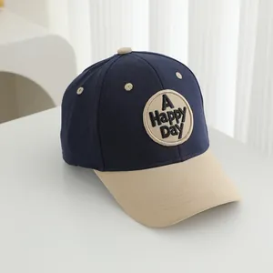 Detail of navy and beige baseball cap featuring a circular A HAPPY DAY embroidery