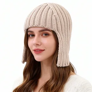 Close-up of beige knit earflap beanie showing thick ribbed texture and warm fabric