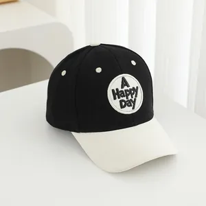 Detail of a black and white baseball cap with 'A HAPPY DAY' embroidery on white cloth