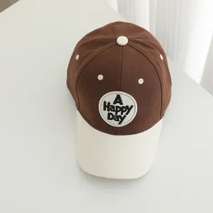 Detail of a brown and cream baseball cap featuring the A HAPPY DAY circular patch design
